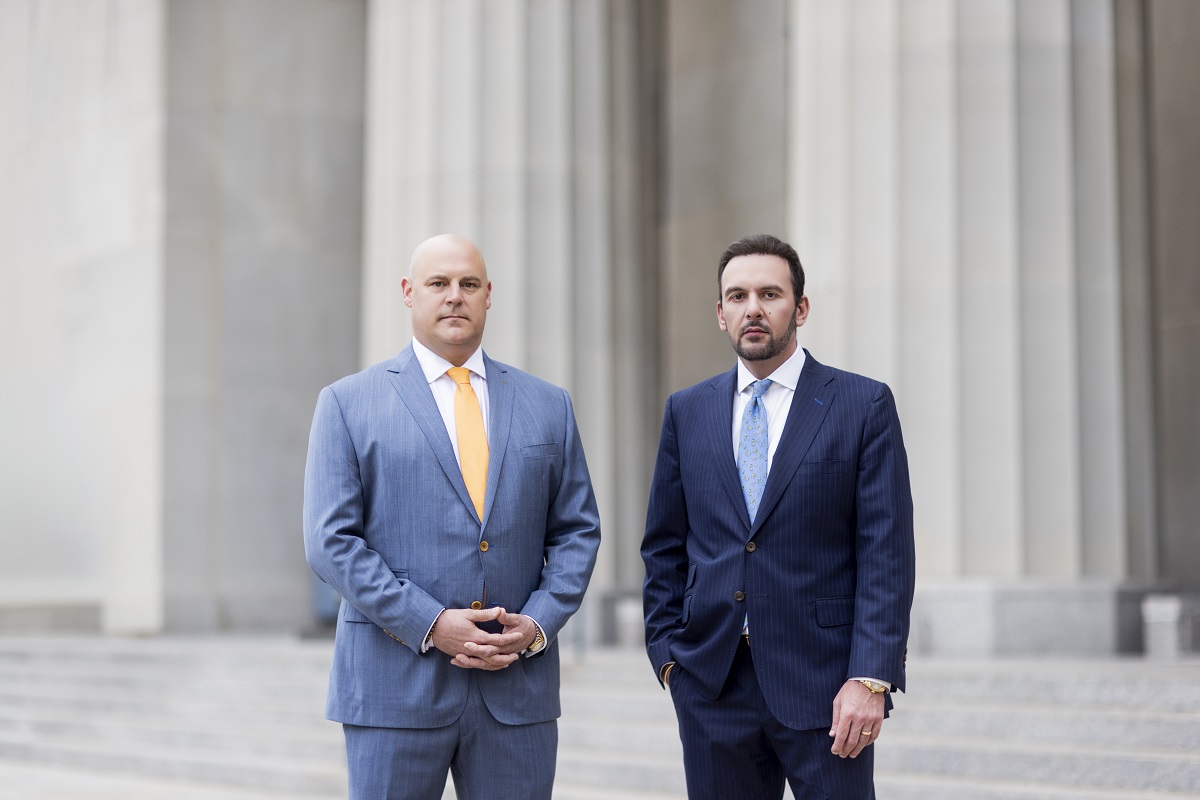 Chris Combs and Steve Waterkotte of Combs Waterkotte standing shoulder-to-shoulder outside a court building.